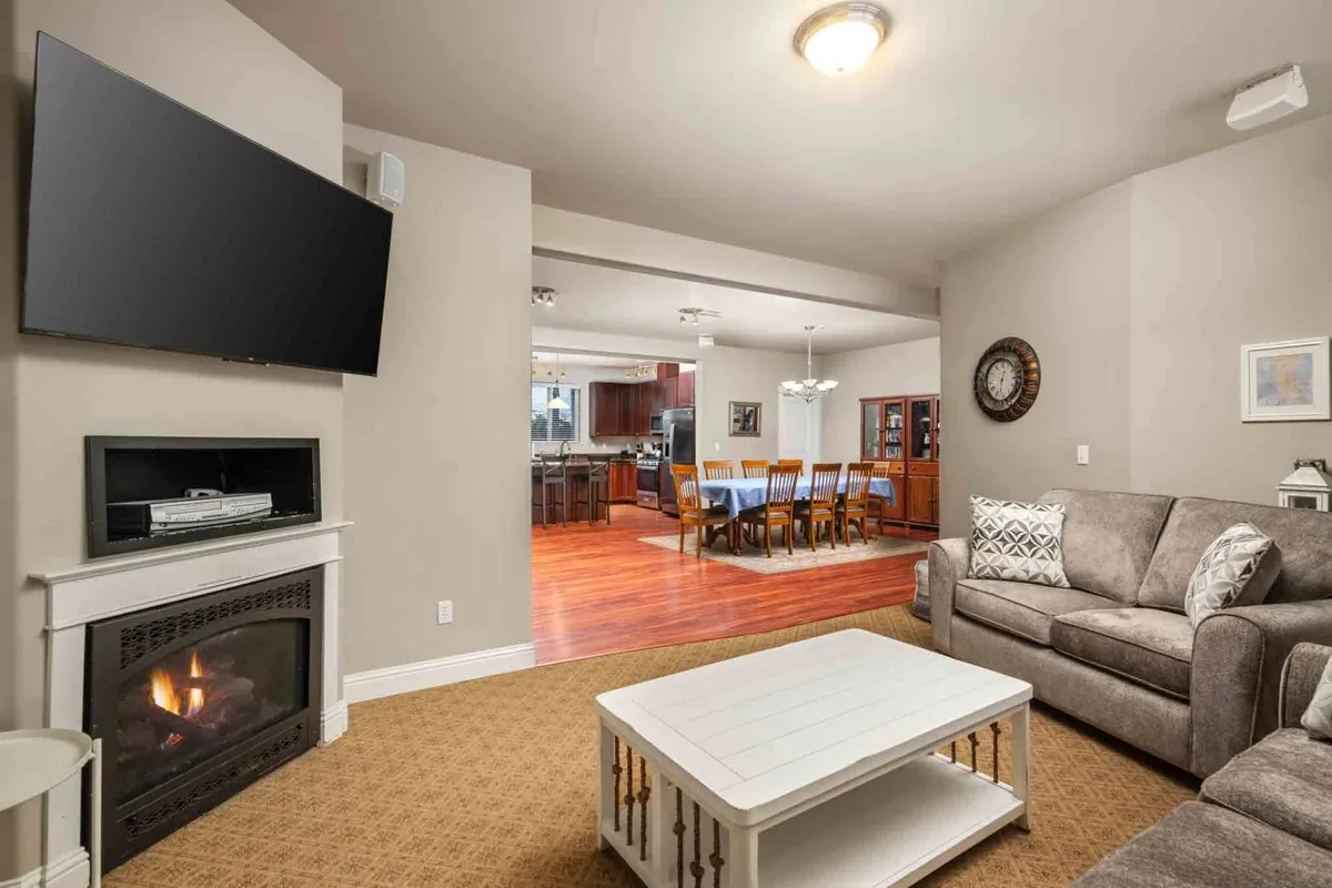 This image showcases a welcoming living and dining area featuring a cozy fireplace, a plush sofa for relaxing, and a dining table perfect for entertaining or sharing meals. The atmosphere is warm and inviting, ideal for gatherings during any season.