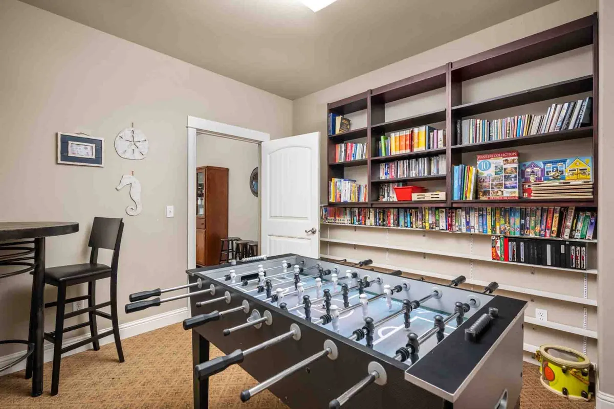 A playful interior scene featuring a foosball table, bookshelf, and bar stools. The space is bright and welcoming, ideal for indoor family fun such as game nights and socializing on rainy days.