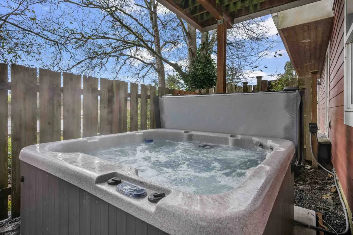 An inviting hot tub surrounded by a fence and trees, offering a private and relaxing outdoor space for guests to unwind in the evening or after a day of exploring.