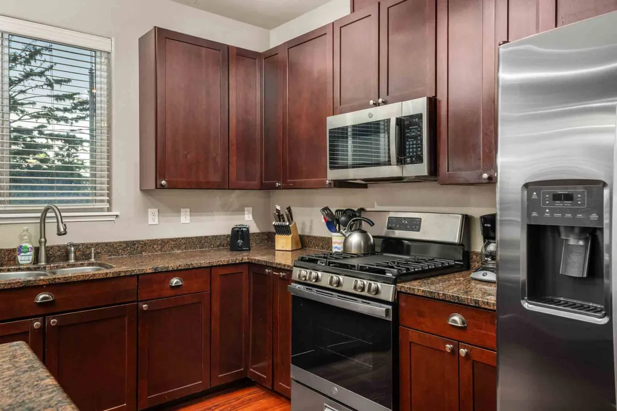 This kitchen scene features modern stainless steel appliances, granite countertops, and warm wooden cabinetry—set up for meal preparation, socializing, and hosting. The space feels inviting and functional, ideal for festive cooking or casual breakfasts.